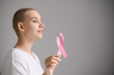 Young woman with pink ribbon on a white background. Mammary cancerの写真素材
