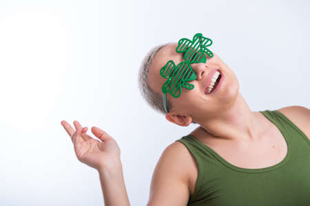 Portrait of a young Caucasian woman with a mans haircut in a green T-shirt and cheerful glasses on a...