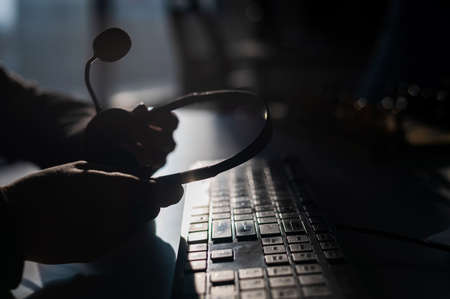 A woman is holding a headset with a microphone over a computer keyboard. Call center operators workplaceの写真素材