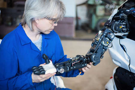 The man assembles a human-like robot and mends his handの写真素材