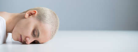 Sad woman sitting with her head on the table on a white background. Widescreen