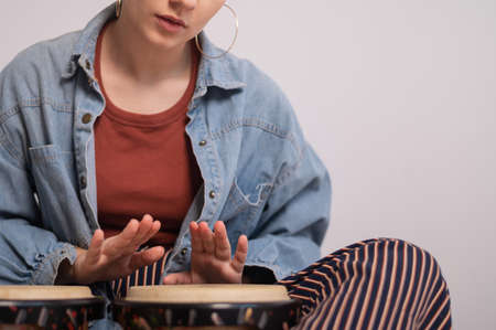 Young faceless Caucasian woman playing small ethnic drumsの写真素材