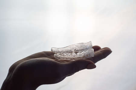 Transparent trays for correcting teeth in female hands. Removable plastic retainersの写真素材