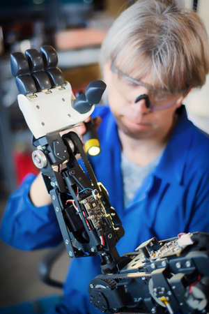 06 april 2019 Russia Novosibirsk: The man assembles a human-like robot and mends his handのeditorial素材