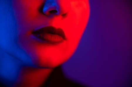 Close-up portrait of beautiful young woman with short hair in neon light. Girl with sensual lips in ultraviolet light.の写真素材