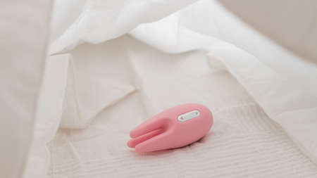 Close-up of a clitoral vibrator on a white sheet on the bedの写真素材