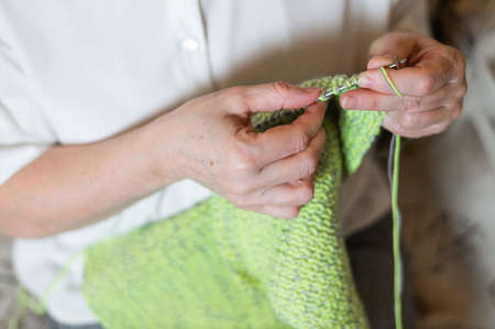The faceless old woman knits. Close-up of female hands with straight and knitting needles.の写真素材