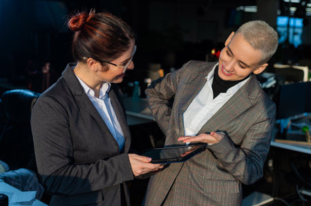 Two young business women looking at digital tablet in office.