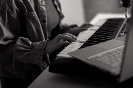 Close-up of female hands on the electric piano. A woman is learning to play the synthesizer on a...