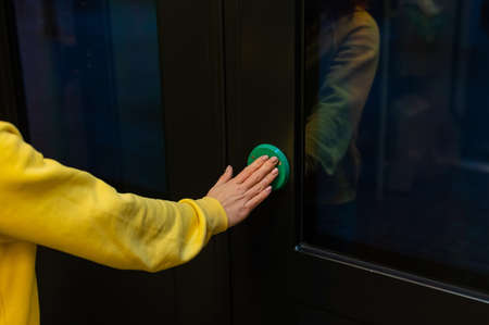 Button for opening doors on the train. Close-up of female hands on the green automatic door opener...