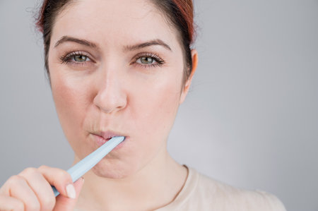 Close-up portrait of caucasian woman brushing her teeth. The girl performs the morning oral hygiene...