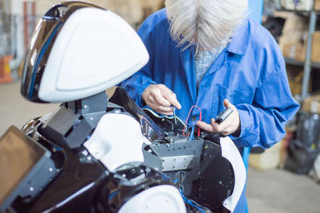 06 april 2019 Russia Novosibirsk: The man assembles a human-like robot and mends his handのeditorial素材