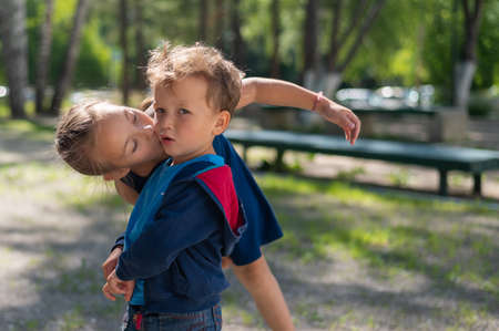 Girl kissing little brother outdoorsの写真素材