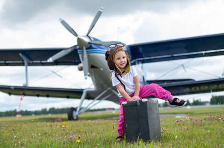 A cute little girl playing on the field by a four-seater private jet dreaming of becoming a pilotの写真素材