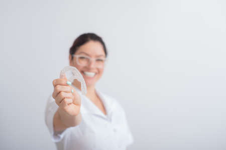 The orthodontist holds the removable transparent retainers