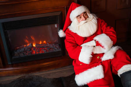 Portrait of Santa Claus sitting by the fireplace for Christmasの写真素材