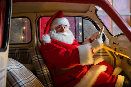 Portrait of santa claus driving a red car for christmas.の写真素材