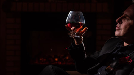 Man drinking whiskey by the fireplace.の写真素材