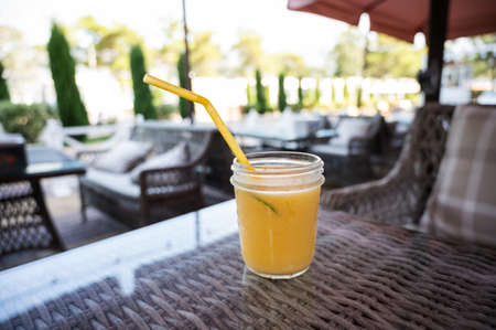 Glass of cold freshly squeezed juice with a straw in an outdoor cafe.の写真素材