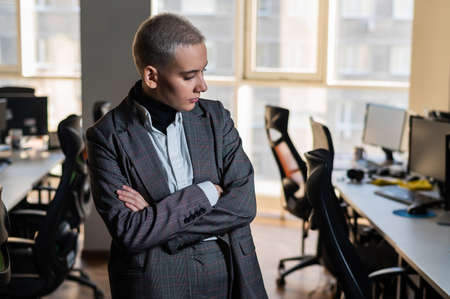 Pensive young woman with short hair sits in armchair in office.の写真素材