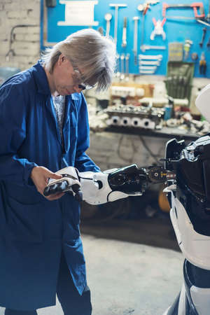 06 april 2019 Russia Novosibirsk: The man assembles a human-like robot and mends his handのeditorial素材
