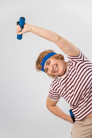 Elderly caucasian woman doing side bends with dumbbells in studio.の写真素材