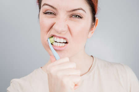 Close-up portrait of caucasian woman brushing her teeth. The girl performs the morning oral hygiene...