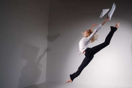 A graceful ballerina in a business suit throws documents in the studio. Business woman dance...