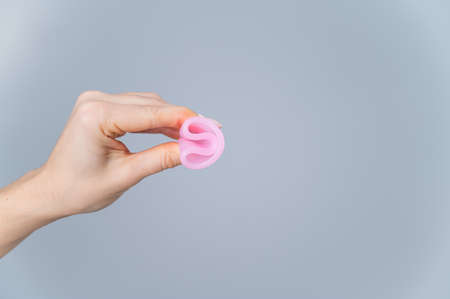Woman holding folded menstrual cup on white background.の写真素材
