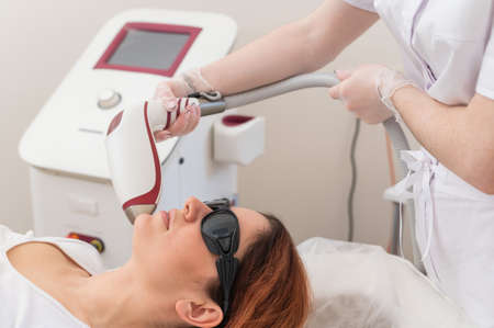 Close-up of laser hair removal on a womans face. The doctor removes unwanted hair from the patient above the lip with an electric deviceの写真素材