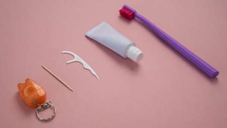 Personal oral hygiene product on a pink background. Toothbrush tube toothpaste toothpick and floss. Flat layの写真素材