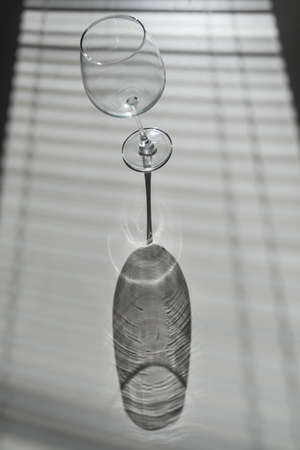Blinds shade on a wine glass on a white table