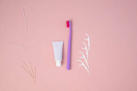Personal oral hygiene product on a pink background. Toothbrush tube toothpaste toothpick and floss. Flat lay. Copy spaceの写真素材