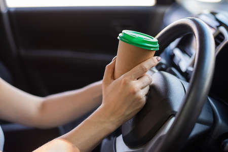 A faceless woman is drinking coffee in a craft glass while driving. Take a hot tonic drink to take awayの写真素材
