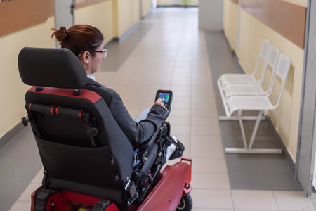 Caucasian woman in electric wheelchair in hospital corridor.