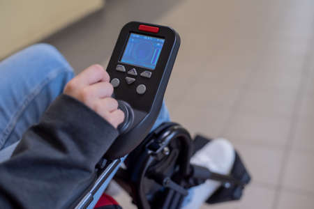 Close-up of a female hand on the control handle of an electric wheelchair