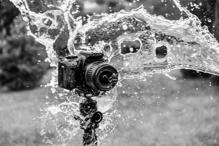 Splashes are flying into a digital camera on a tripod.の写真素材