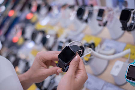 Faceless caucasian woman chooses a smart watch in an electronics storeの写真素材