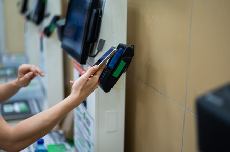 Woman paying with smartphone in store at self-checkout counter.の写真素材