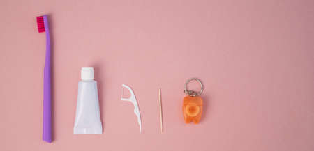 Oral hygiene products on a pink background. Toothbrush toothpaste dental floss and toothpick. Copy...