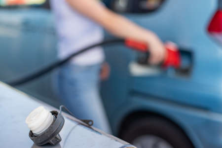 Caucasian woman refueling a car at a self-service gas station.の写真素材