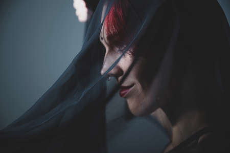 Profile of a woman in a black veil. Costume Dead bride for Halloween. Portrait of an evil grinning Witch in front of a coven.の写真素材