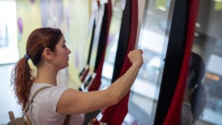 Woman uses touch information desk in shopping mall.