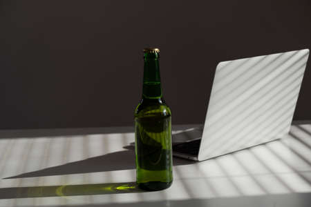 Beer bottle and laptop on white table.の写真素材
