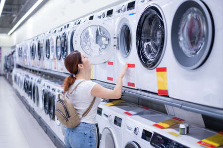 Caucasian woman chooses a washing machine in a home appliances storeの写真素材