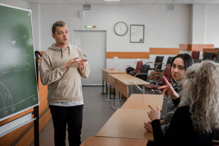 Two girls and a guy are talking in sign language. Three deaf students chatting in a university...
