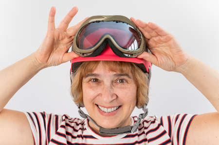 An elderly woman puts on a pink ski helmet on a white backgroundの写真素材