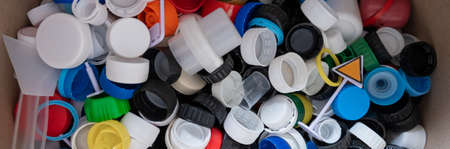 A close-up of many plastic bottle caps collected for recycling.