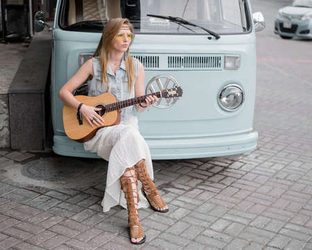 26.07.2020 Russia, Novosibirk: A hippie girl plays an acoustic guitar leaning against a classic Volkswagen T1のeditorial素材
