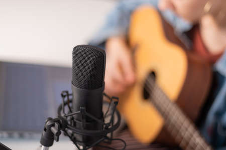 Faceless woman playing guitar and streaming live on laptop.